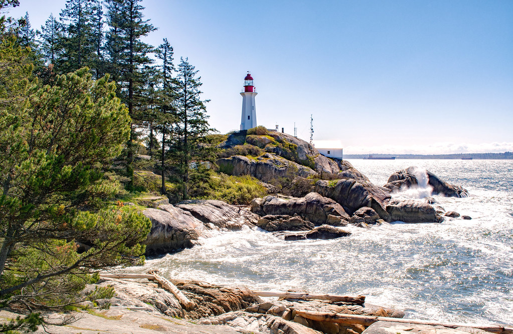 Couple standing on coastal rocks at Lighthouse Park with ocean views at sunset.