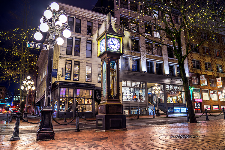 Engagement photo on a cobblestone street in Gastown with warm string lights overhead.