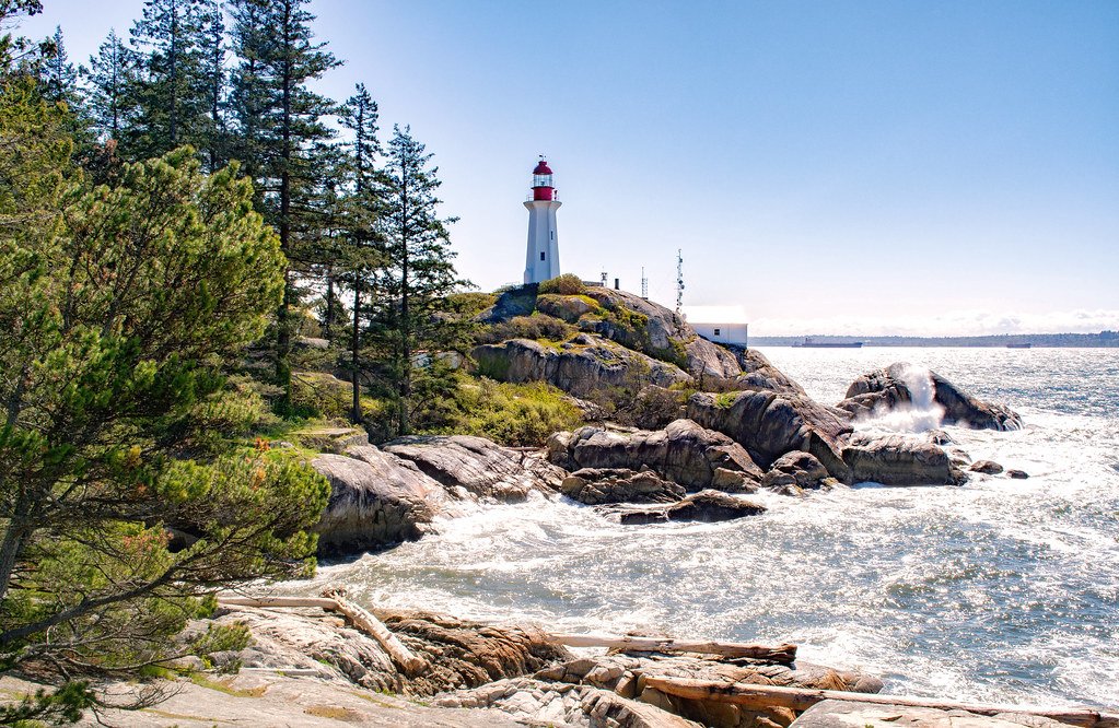 Couple standing on coastal rocks at Lighthouse Park with ocean view.