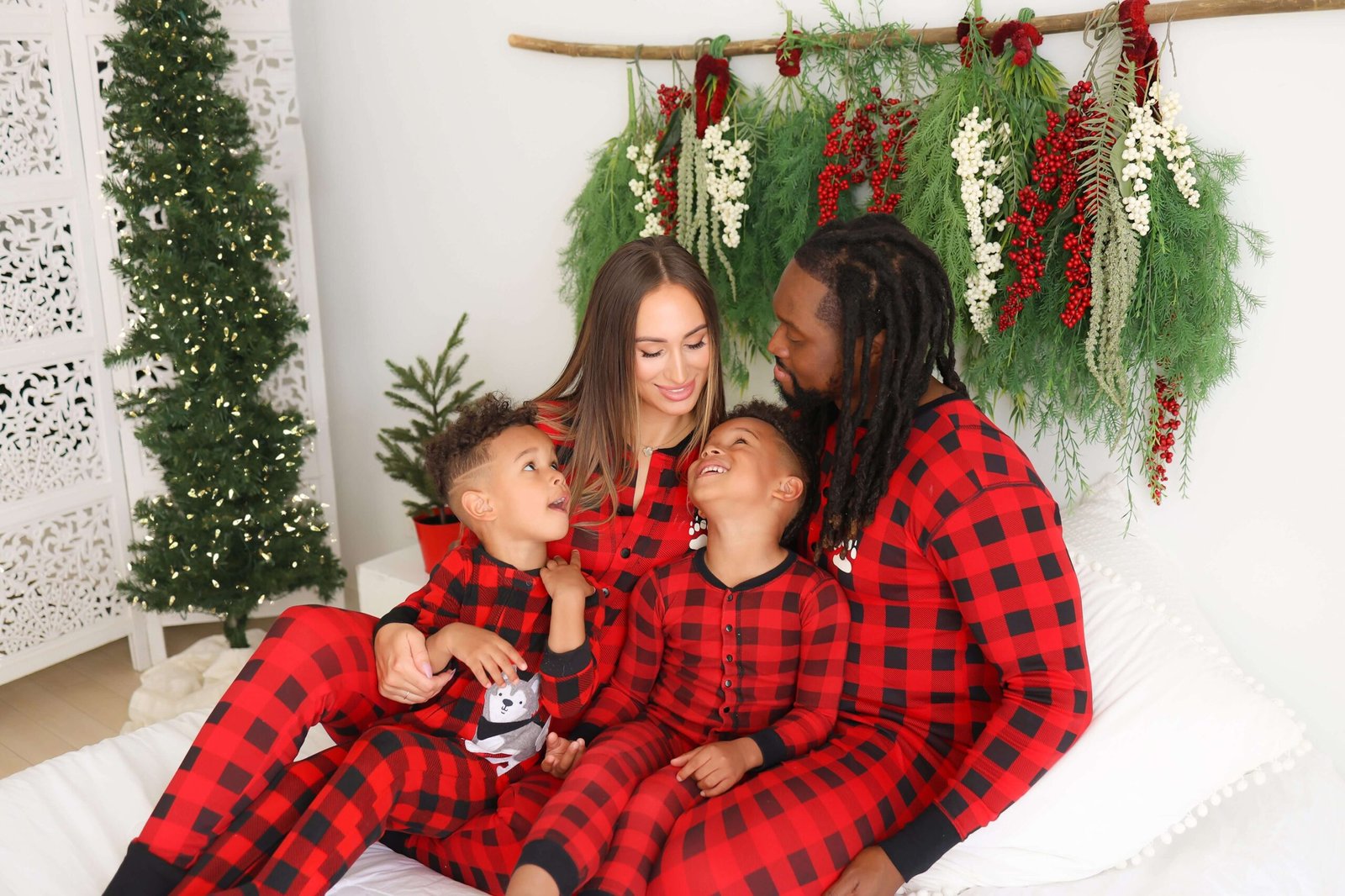 Family sitting on a bed with a holiday wreath backdrop
