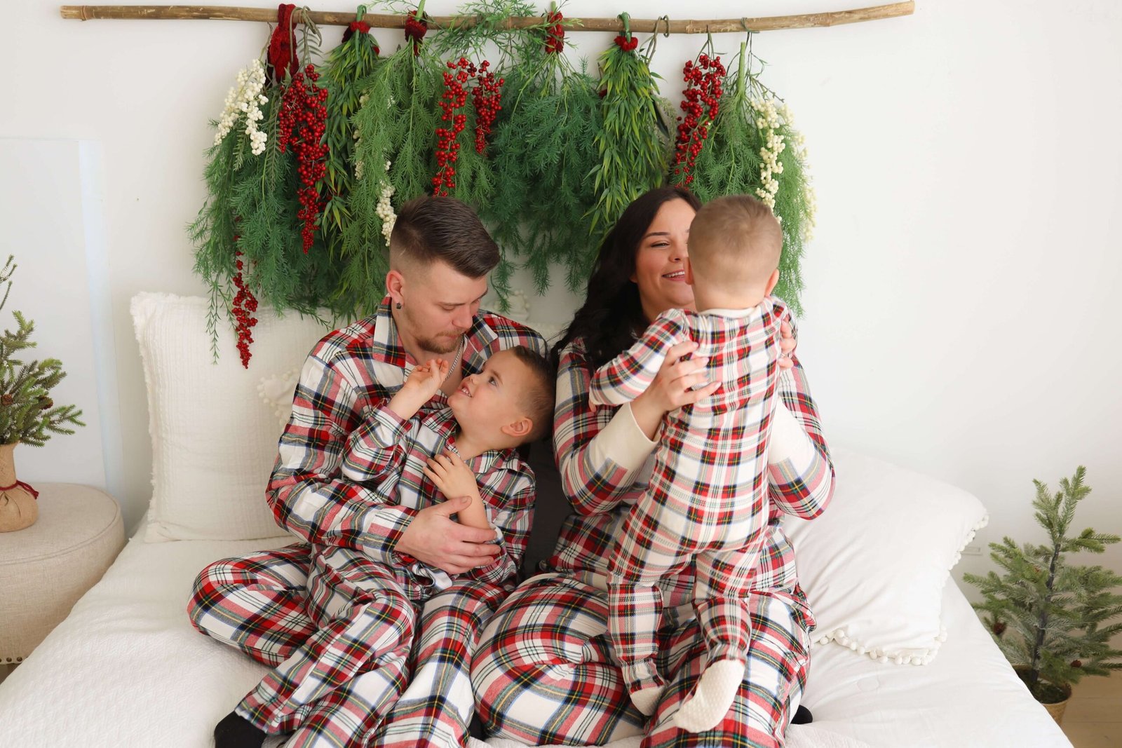 Parents cuddling on a bed with subtle Christmas greenery decor