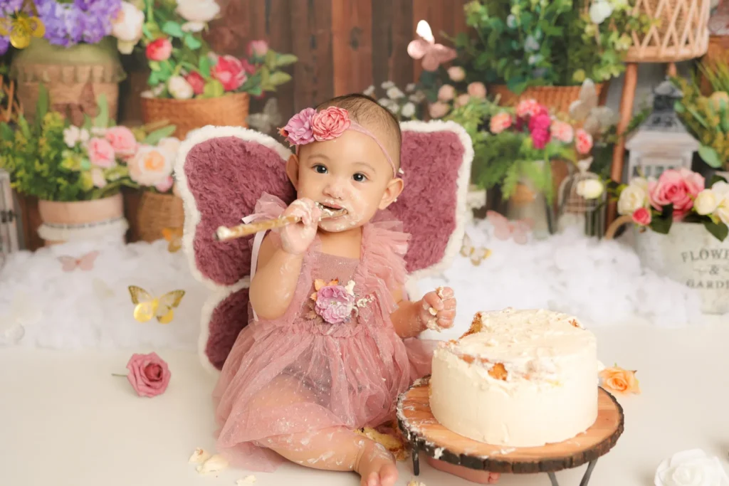 Baby sitting beside cake with fairy wings during cake smash