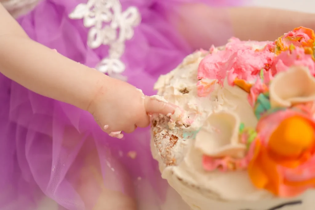 Child reaching toward cake with colorful frosting