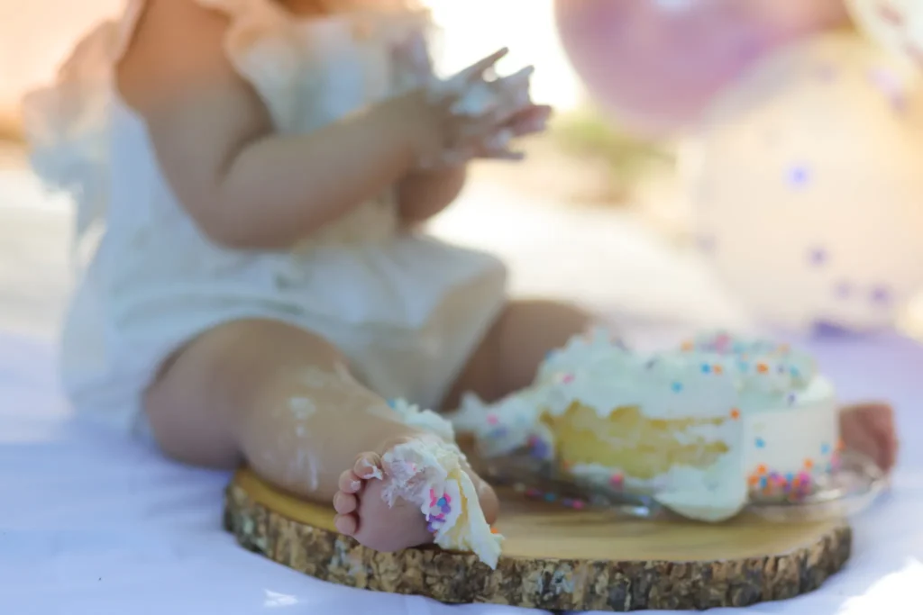 Close up of baby hands and toes touching birthday cake