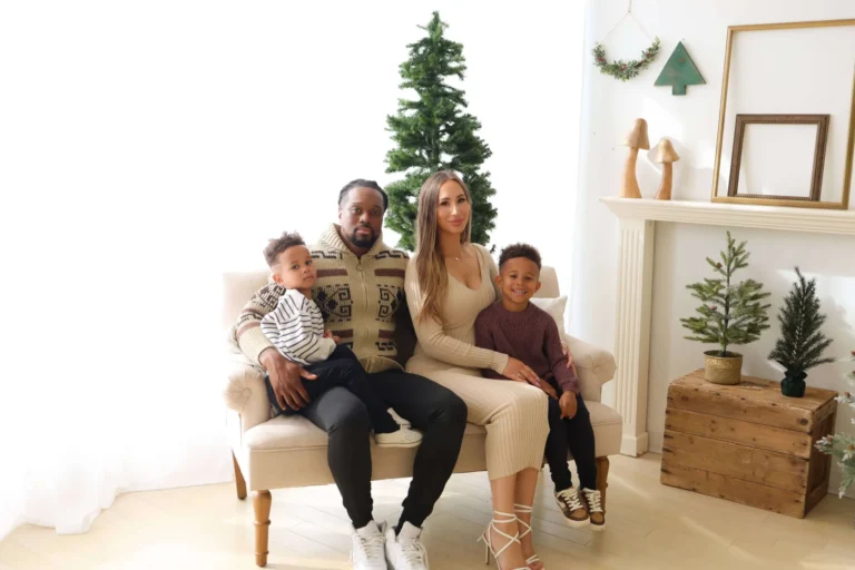 Family on studio sofa with small Christmas tree backdrop scaled 1