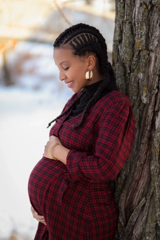 Pregnant woman leaning against tree during maternity session