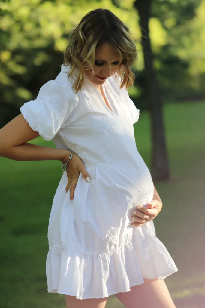 Pregnant woman posing outdoors in white dress