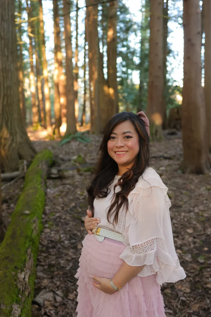 Pregnant woman standing in forest holding belly