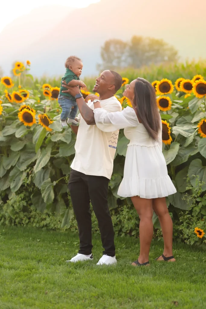 parents lifting toddler sunflower field scaled 1