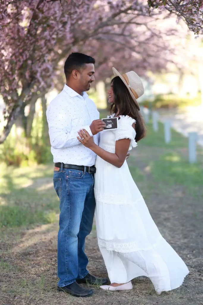 Couple standing together under blooming cherry blossom trees during engagement session.jpg