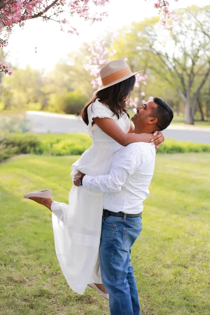 Expecting couple celebrating pregnancy under blooming trees during spring maternity photoshoo.jpg