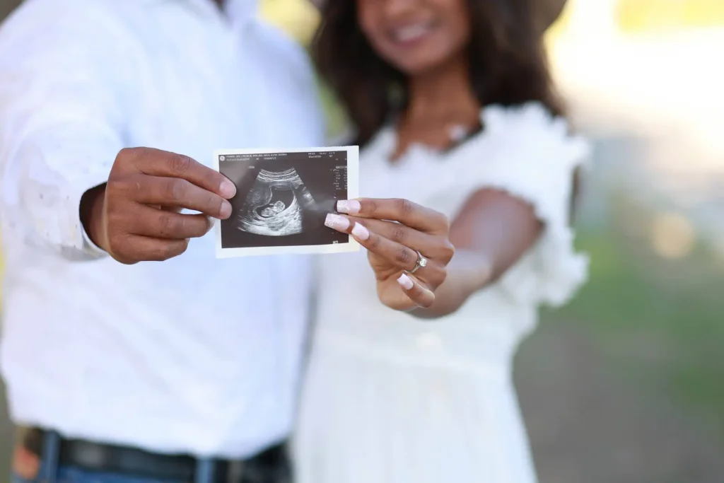 Expecting couple holding ultrasound photo during outdoor maternity photography session.jpg