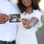 Expecting couple holding ultrasound photo during outdoor maternity photography session.jpg