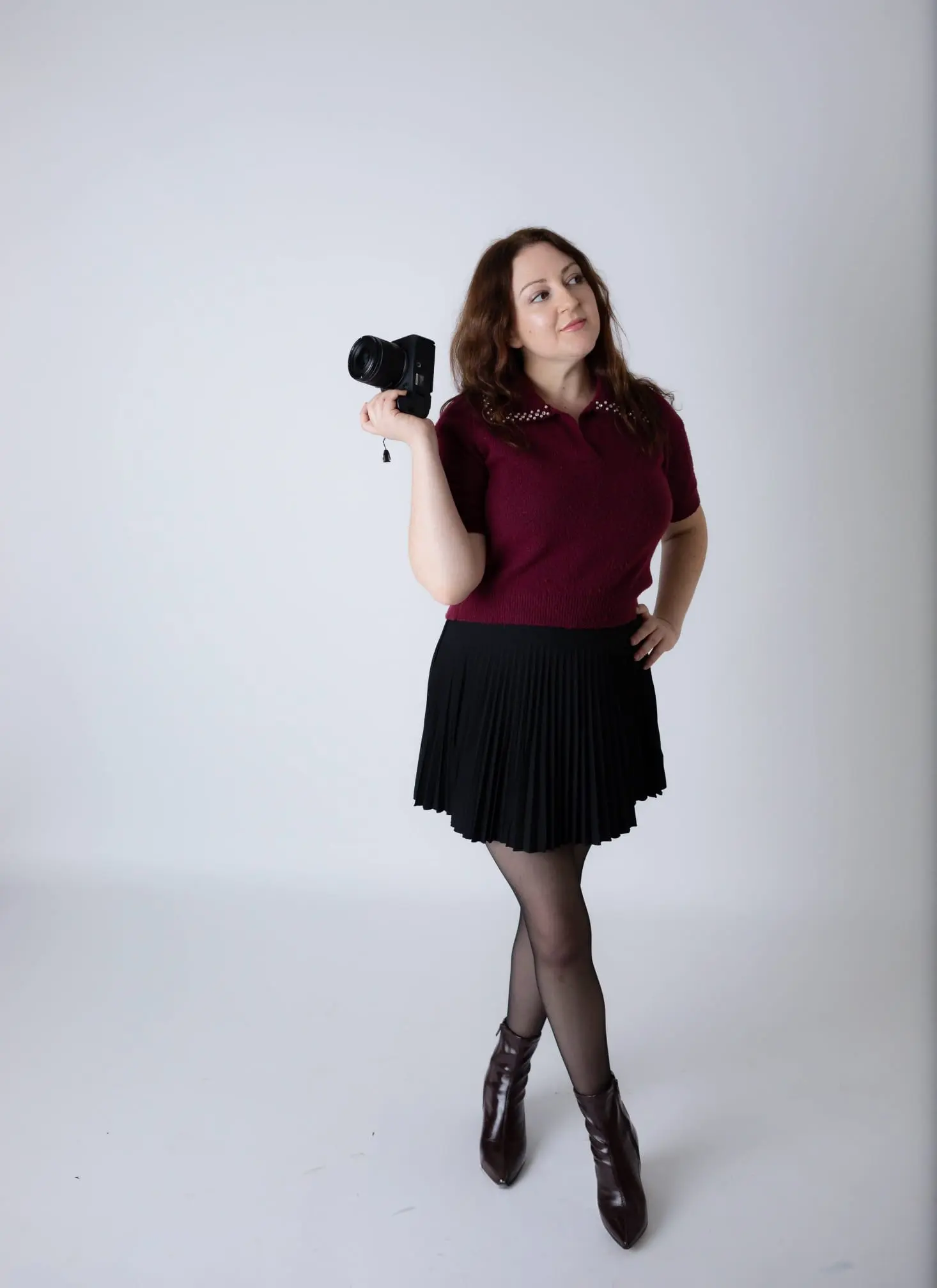 Natalia Vaxman standingwith her professional camera in a clean studio setting.