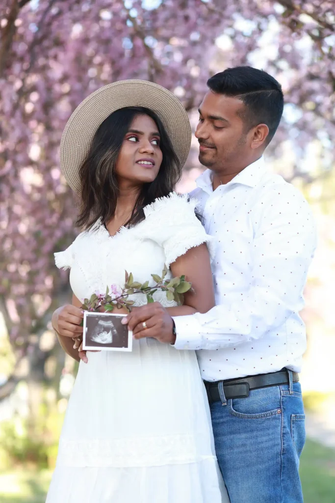 Pregnant couple posing together under spring blossoms during maternity photoshoot.jpg