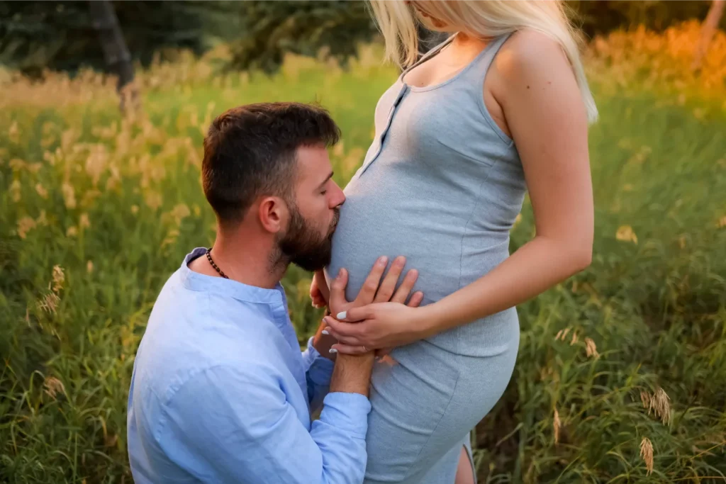 father kissing baby bump outdoor