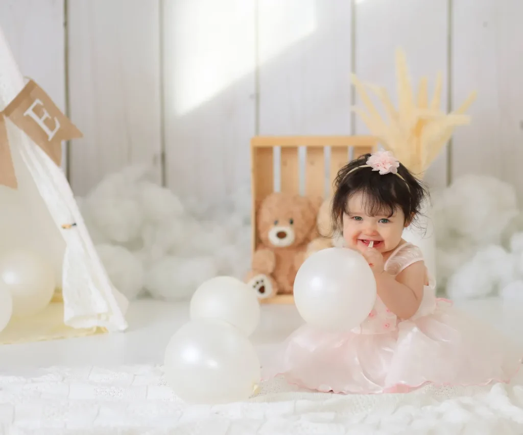 baby girl playing with white balloons