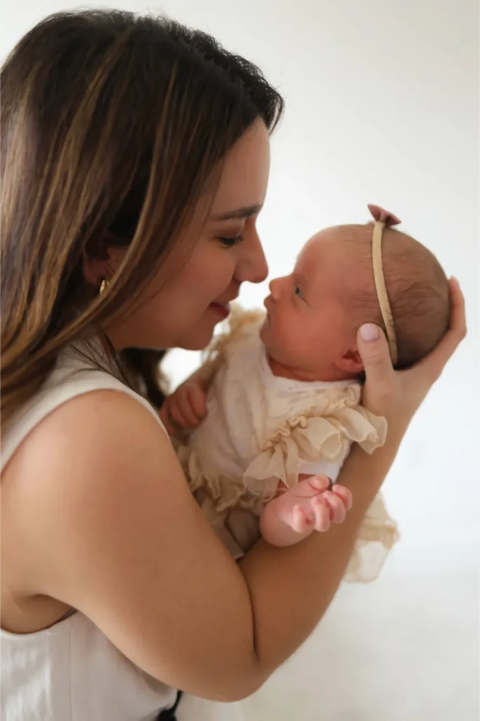 mother kissing newborn baby portrait