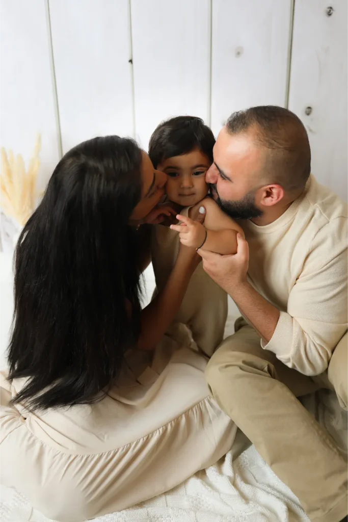 parents kissing baby boy family portrait