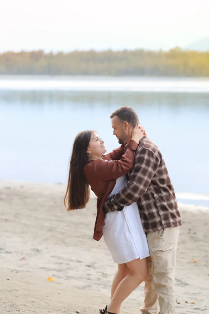 Couple embracing by the lakeshore at sunset