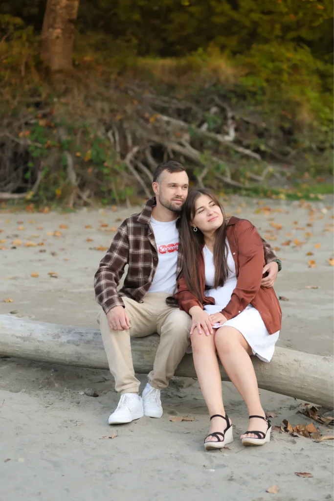 Couple sitting together on driftwood by the river