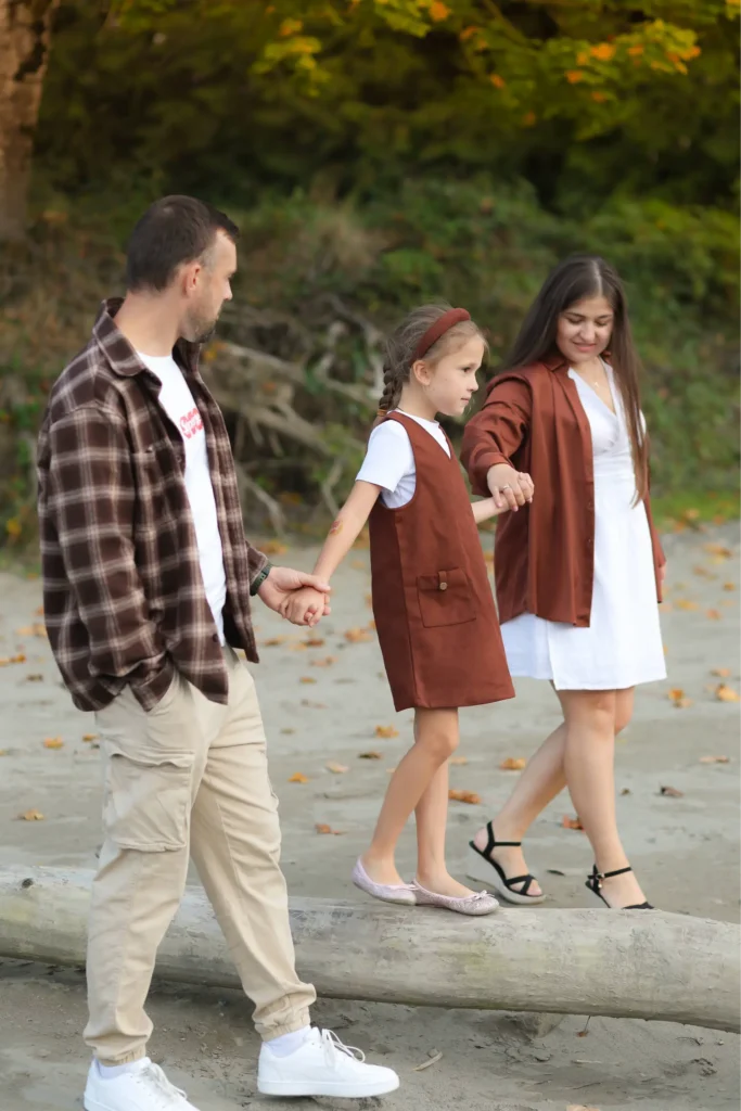 Couple walking along riverbank with their daughter during fall session