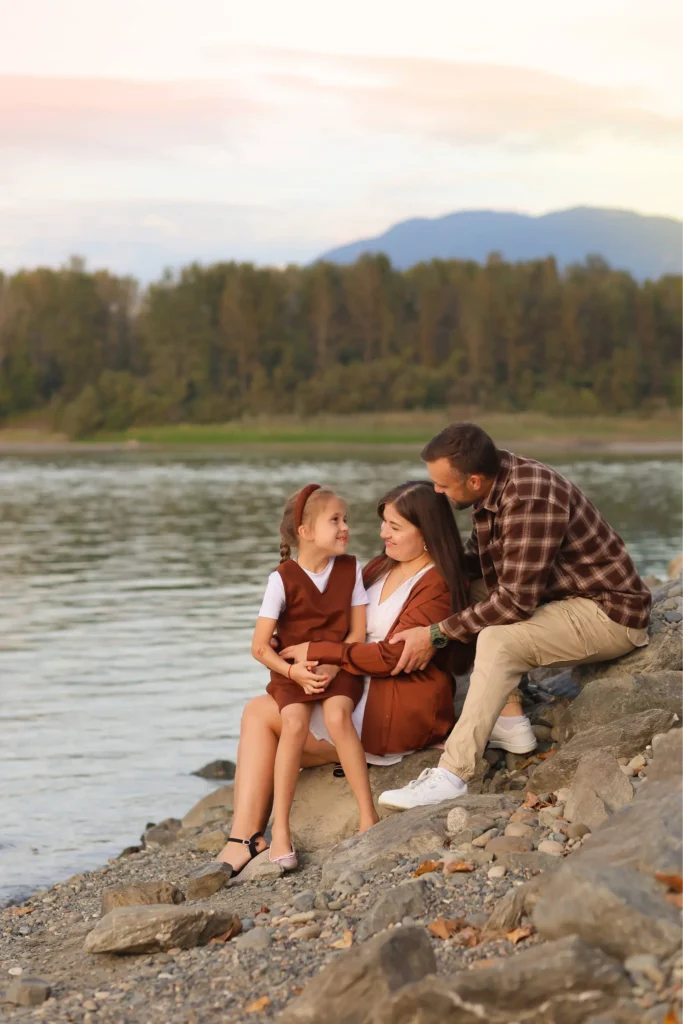 Family sitting by the river at Island 22 Regional Park Chilliwack