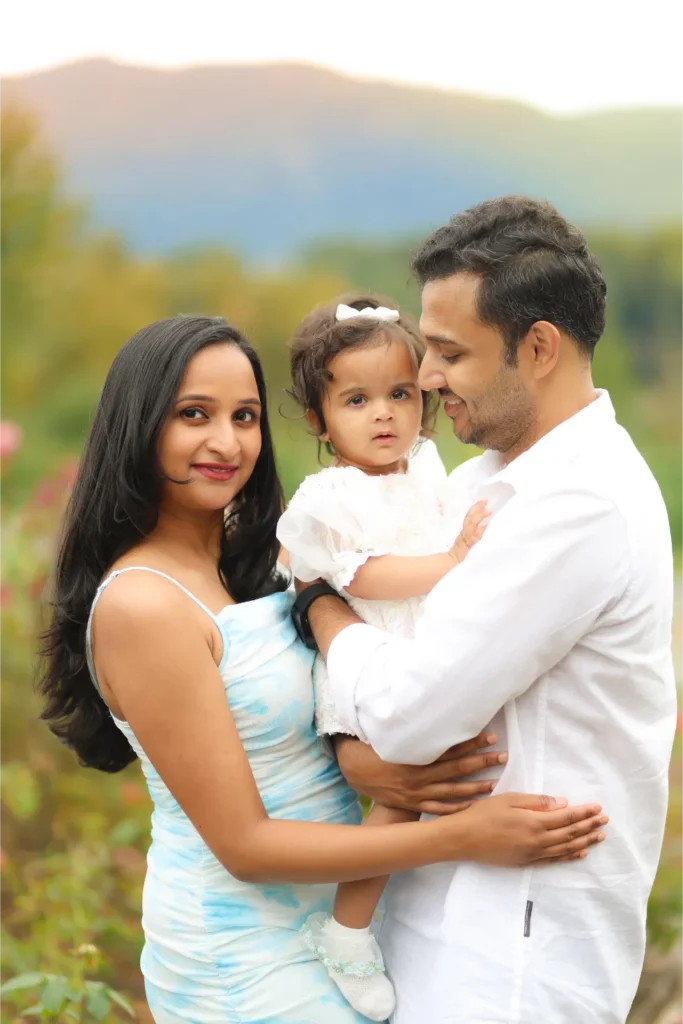 parents holding baby girl sunset