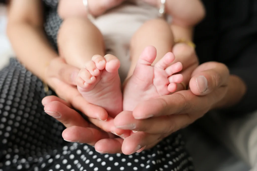 adult hands holding baby feet
