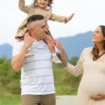father carrying daughter shoulders maternity session