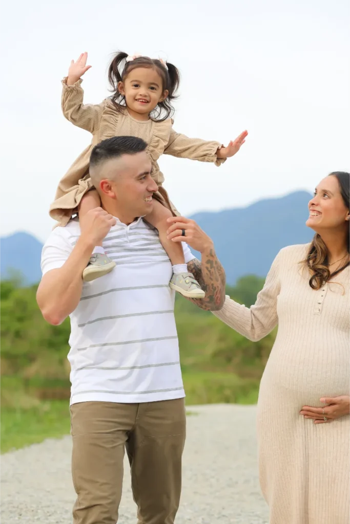 father carrying daughter shoulders maternity session