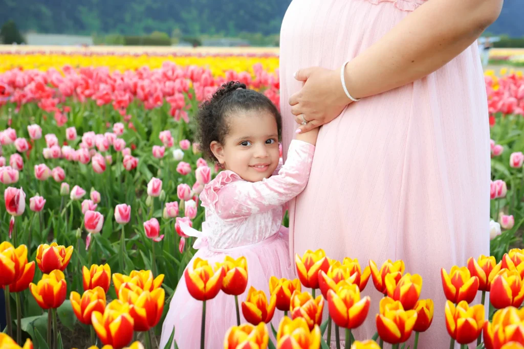 daughter touching pregnant belly tulips