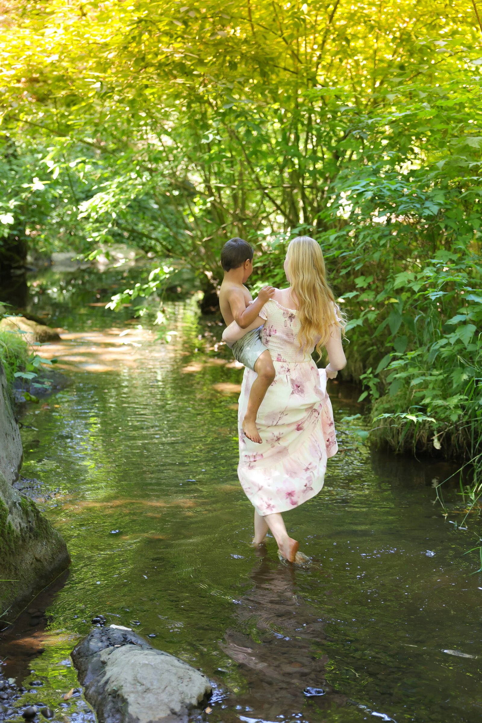 Mother carrying her child through a peaceful forest creek