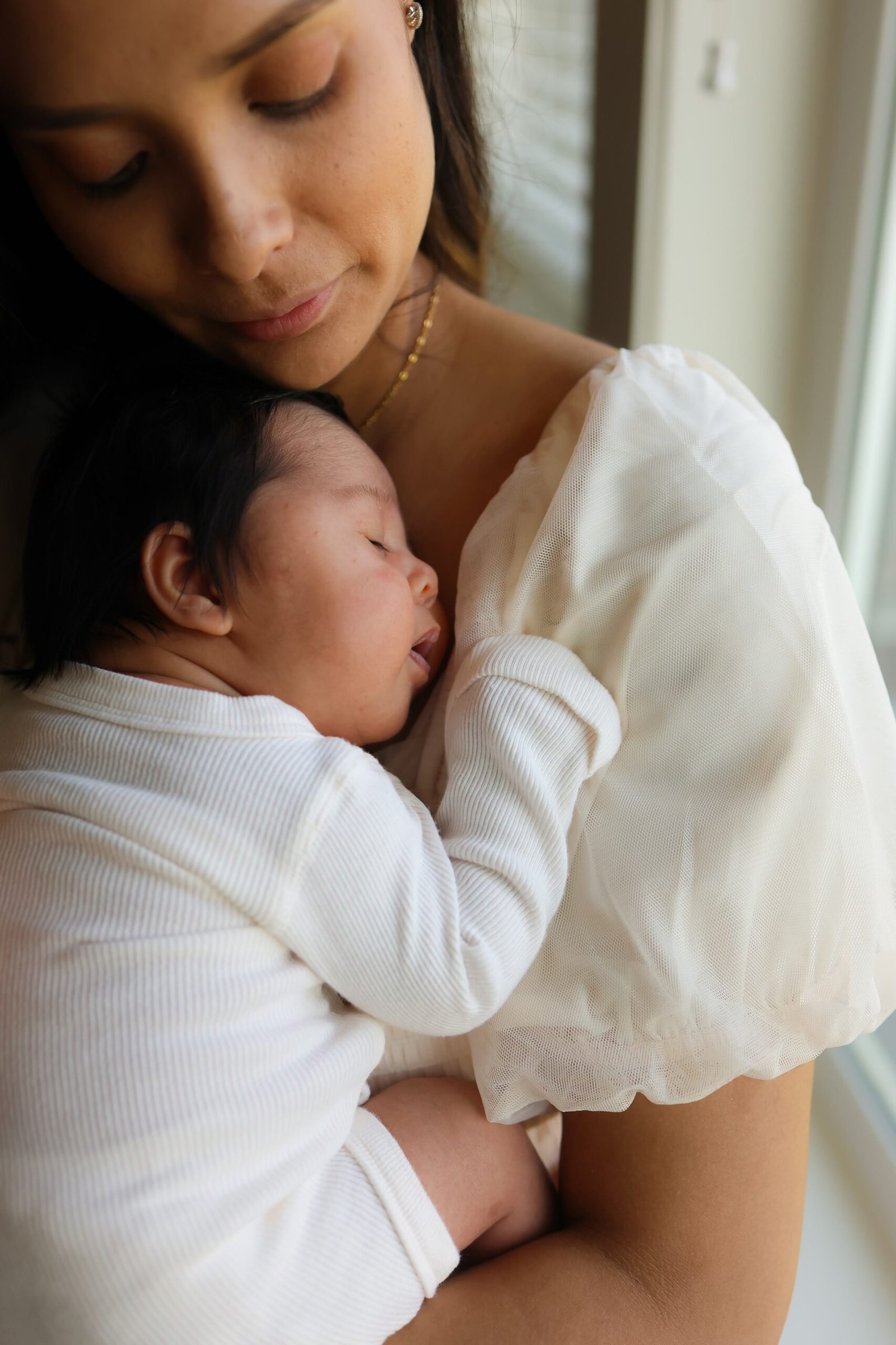Mother cradling her sleeping newborn at home