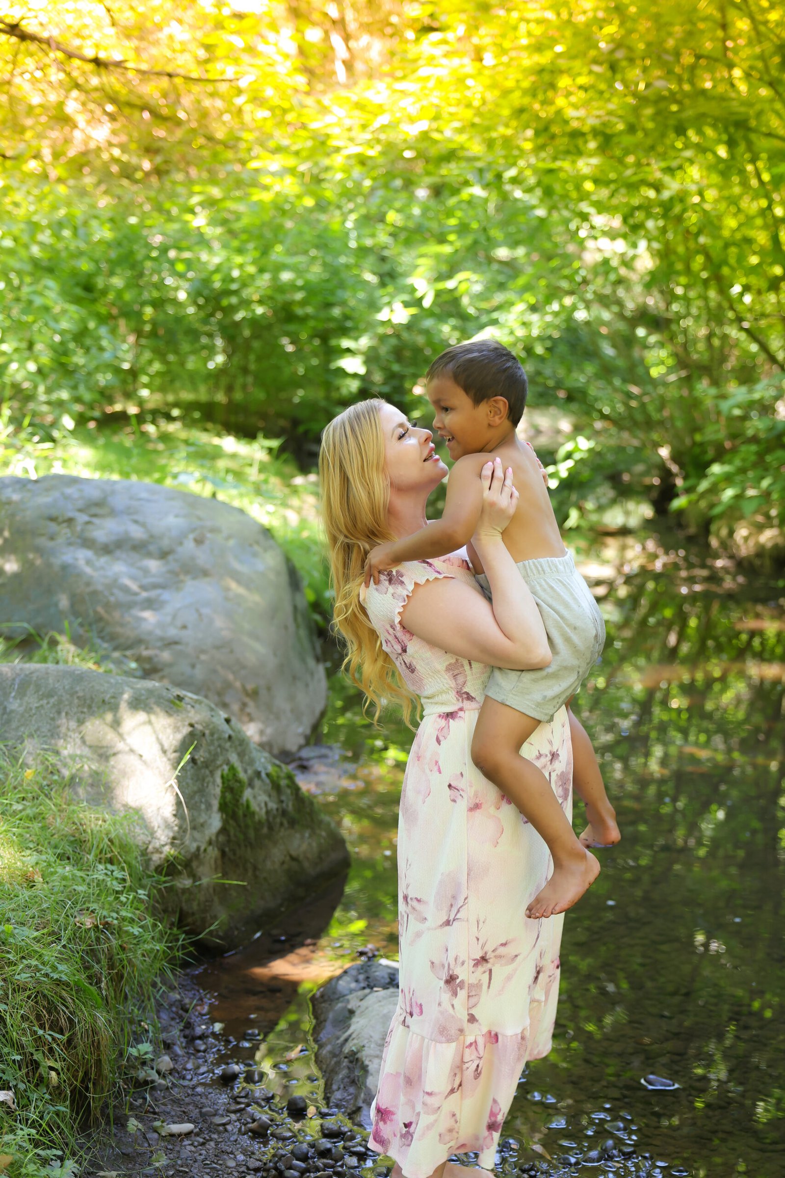 Mother and child sharing a sweet moment beside a forest creek
