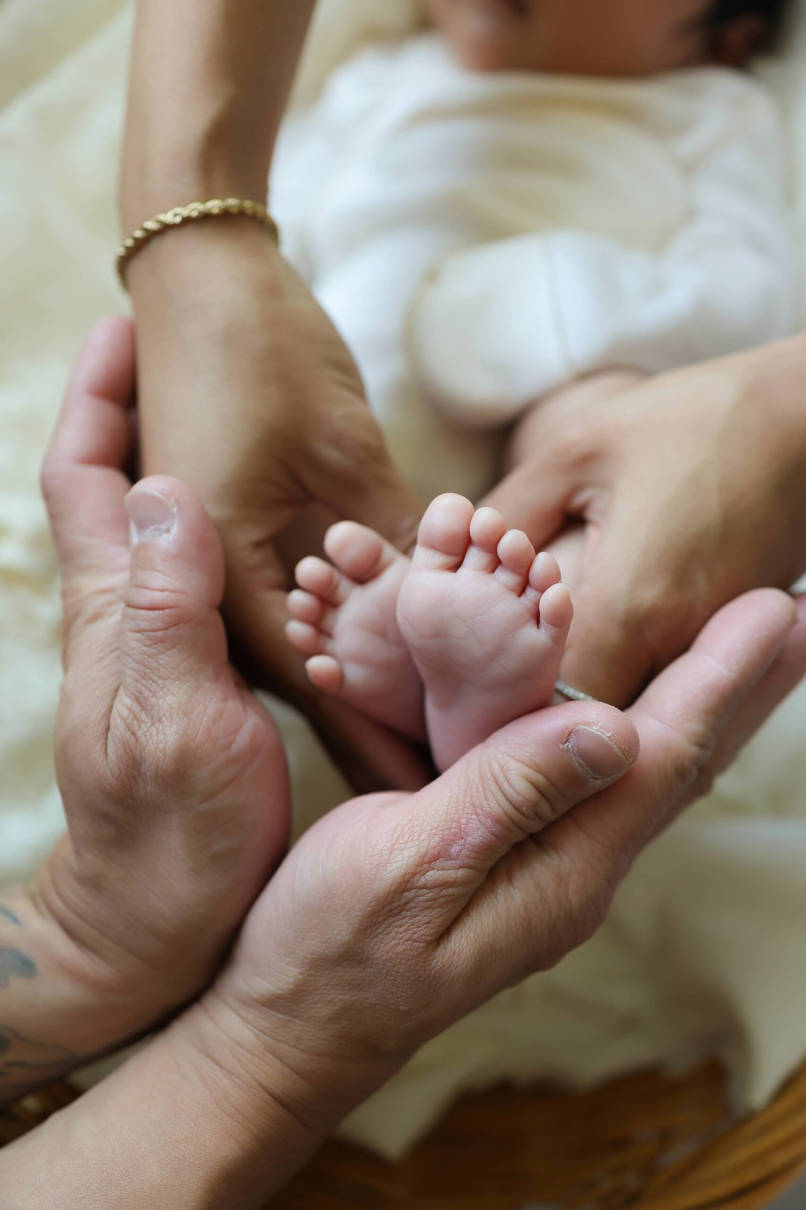 Close-up of newborn feet cradled in parents' hands