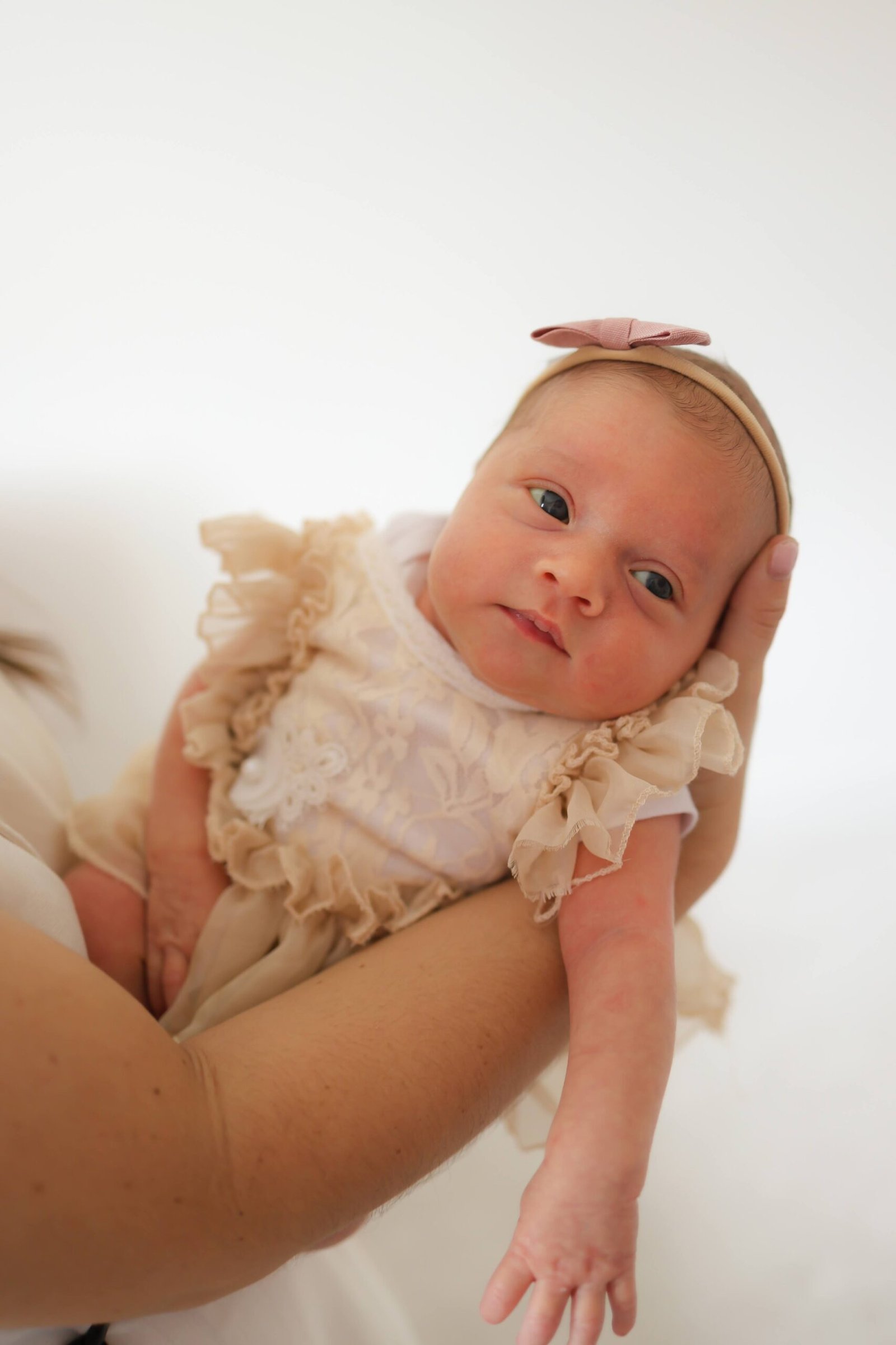 Newborn girl held gently for a studio portrait
