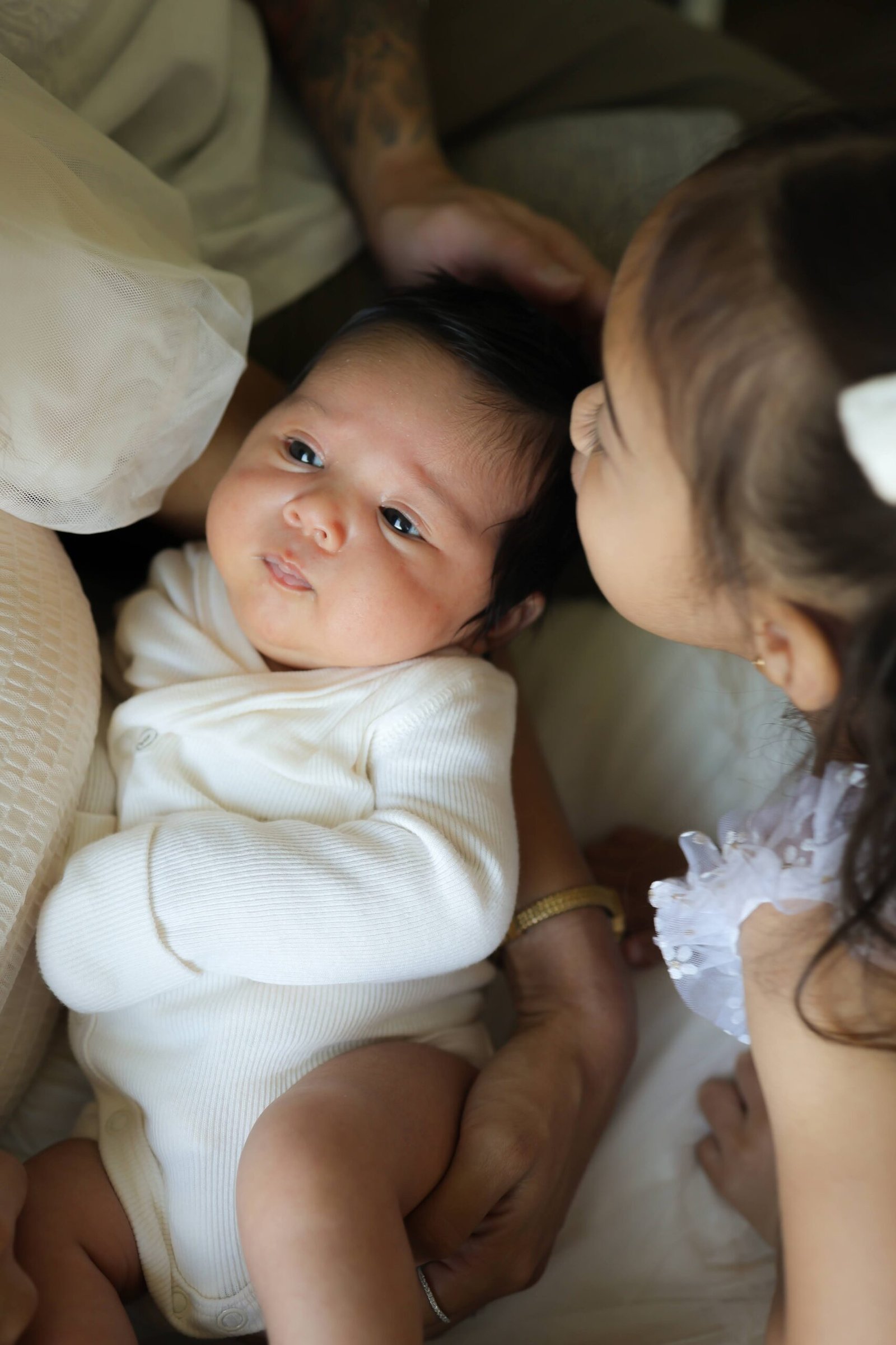 Older sister kissing her newborn sibling