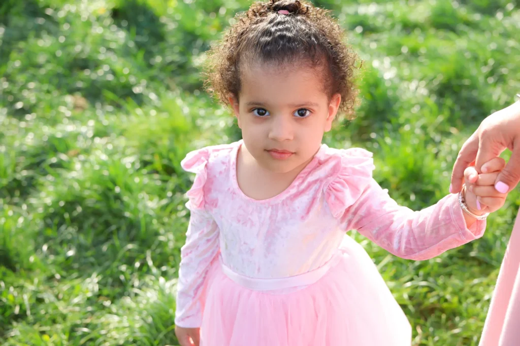 young girl pink dress holding hand