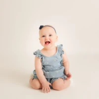 Baby sitting alone on neutral background smiling Baby sitting alone on neutral background smiling