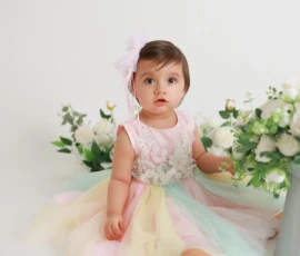 Baby sitting beside floral arrangement indoors