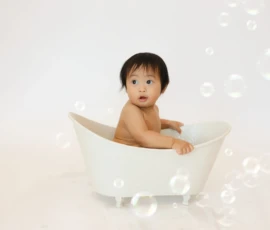 Baby sitting in bathtub surrounded by soft bubbles