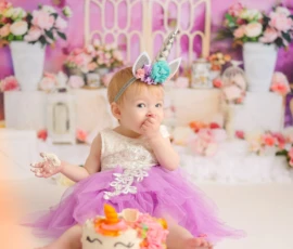 Baby sitting in pink birthday setup with cake