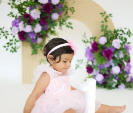 Baby sitting near floral arch during milestone session