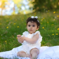 Baby sitting on blanket outdoors in soft light Baby sitting on blanket outdoors in soft light