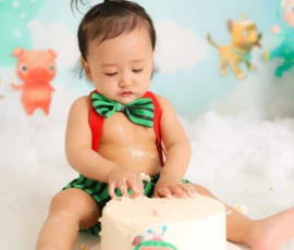 Baby sitting with cake during colorful cake smash session