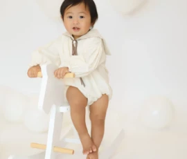 Baby standing on stool with neutral backdrop