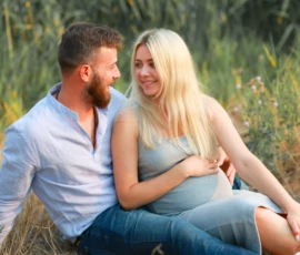 Couple sitting close together in tall grass at golden hour Couple sitting close together in tall grass at golden hour