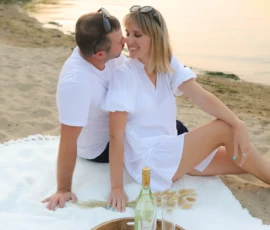 Couple sitting on blanket by water during sunset Couple sitting on blanket by water during sunset