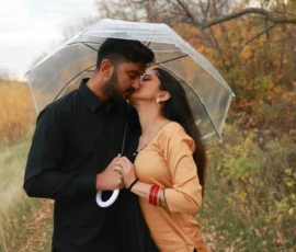 Couple standing close together under umbrella in fall setting Couple standing close together under umbrella in fall setting